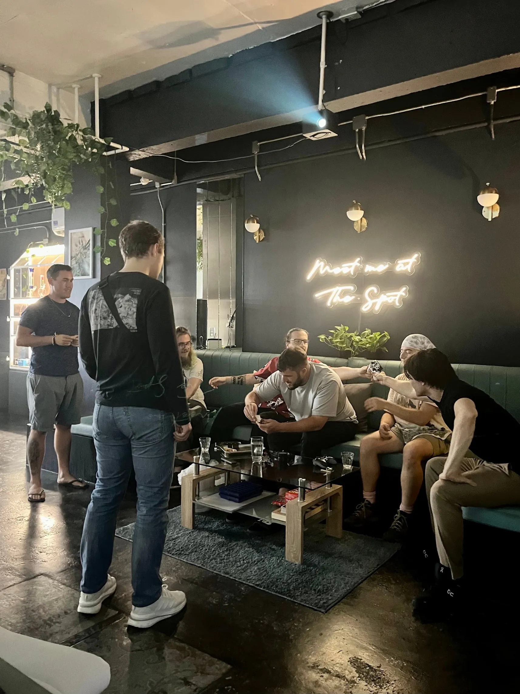 The lounge on the second floor, people sitting on sofas and low tables under the Meet me at The Spot neon