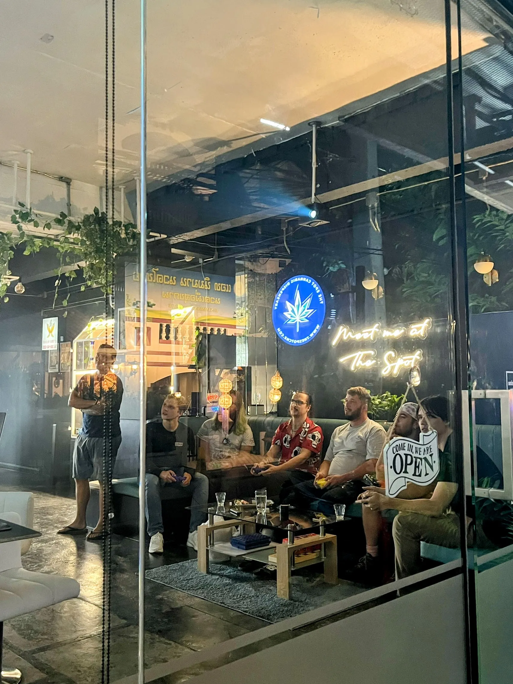 The lounge inside The Spot at night, customers on the sofas under the Meet me at The Spot neon