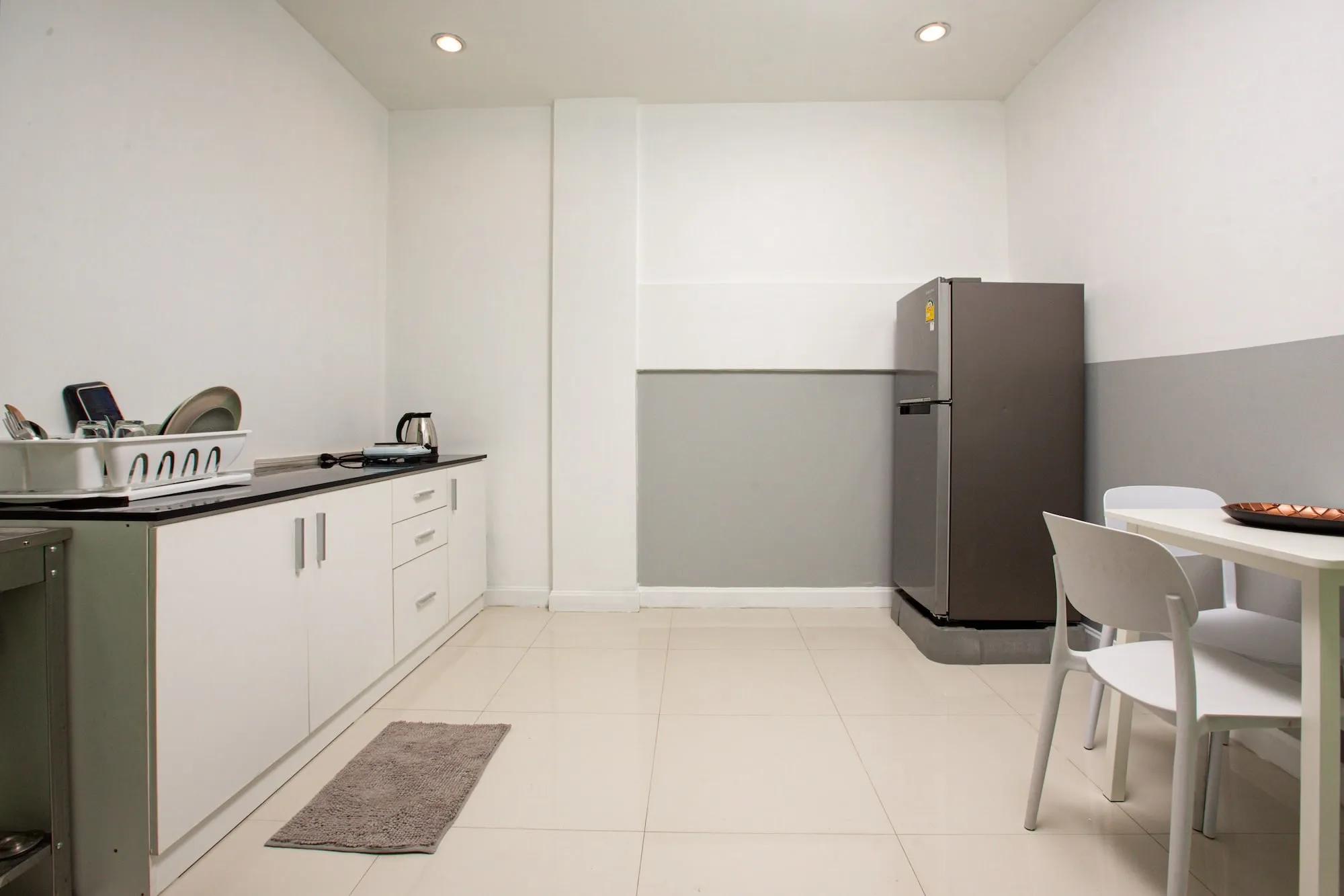 The kitchen in a Safehouse apartment, hob and sink along a counter with a fridge and a small dining table