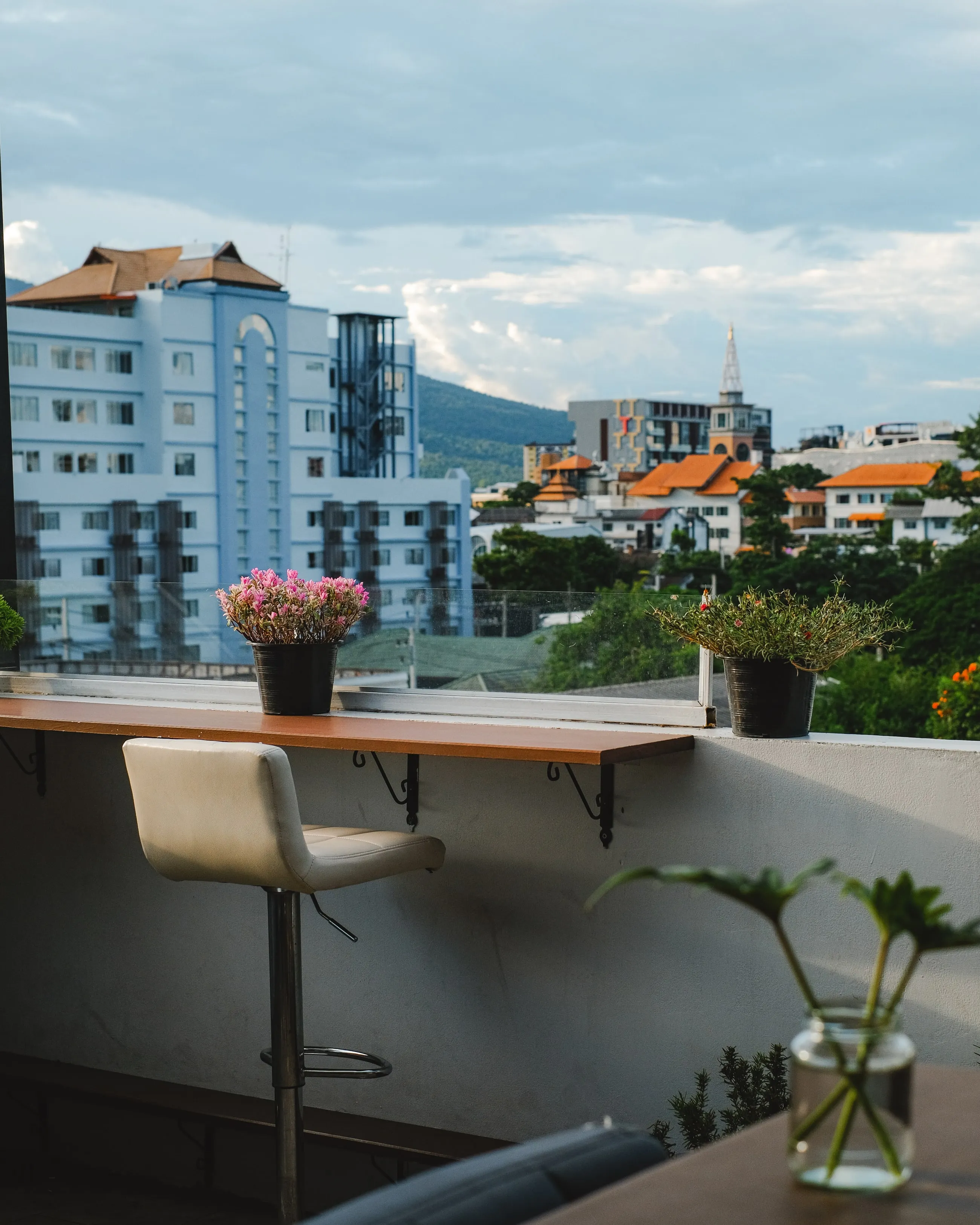 The Sway CNX counter in daylight, open to the rooftop, with the mountains behind Chiang Mai in the distance