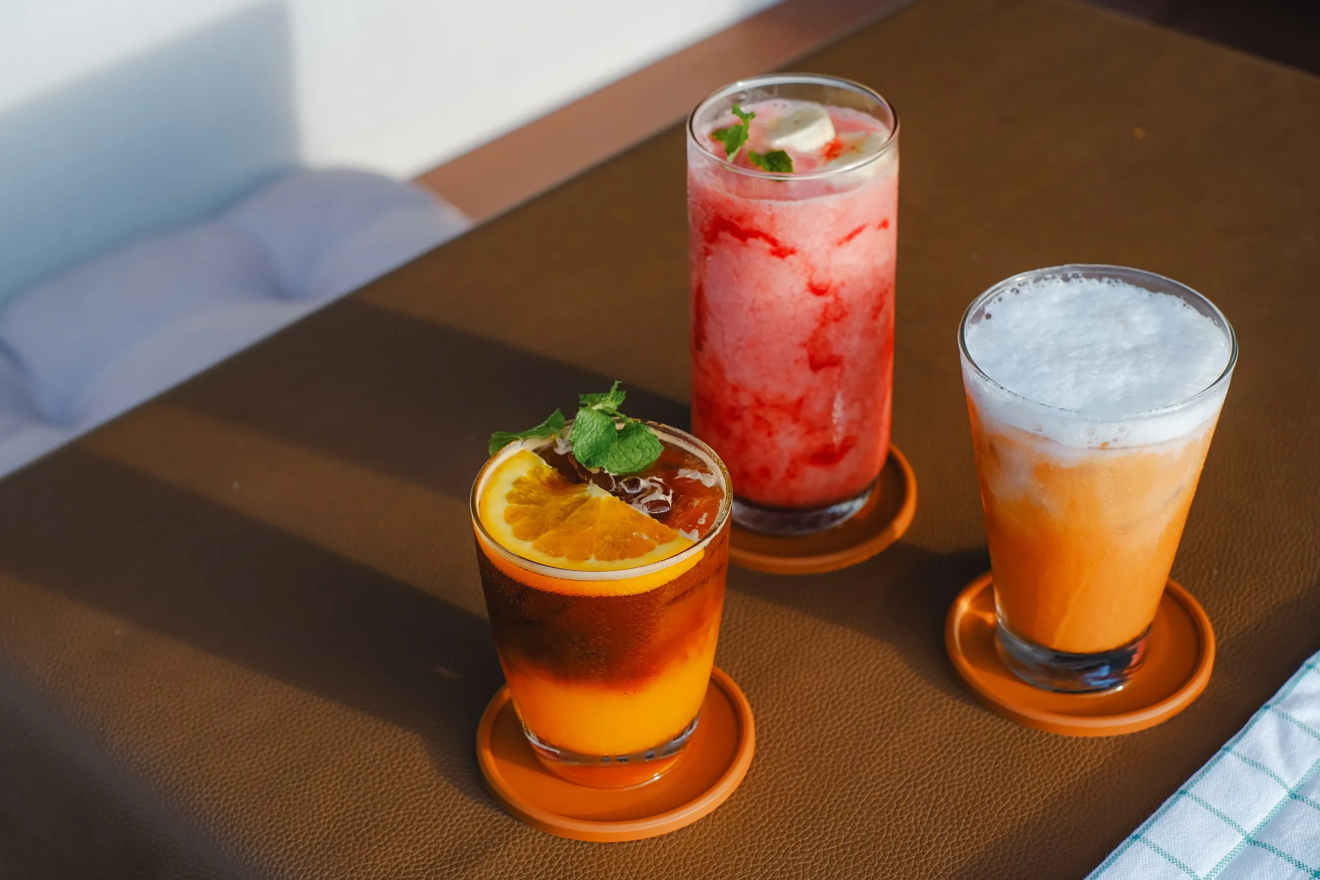Three iced drinks on a wooden table at Sway CNX